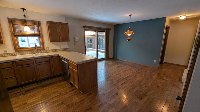 kitchen with dark wood finished floors, stainless steel dishwasher, a healthy amount of sunlight, a sink, and a peninsula