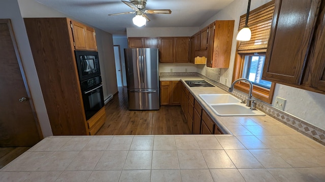 kitchen featuring tile countertops, a ceiling fan, a sink, tile patterned flooring, and black appliances