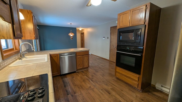 kitchen featuring tile counters, a baseboard heating unit, a sink, a peninsula, and black appliances