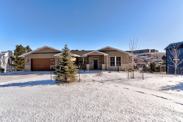 view of front of property featuring a garage, stone siding, board and batten siding, and driveway