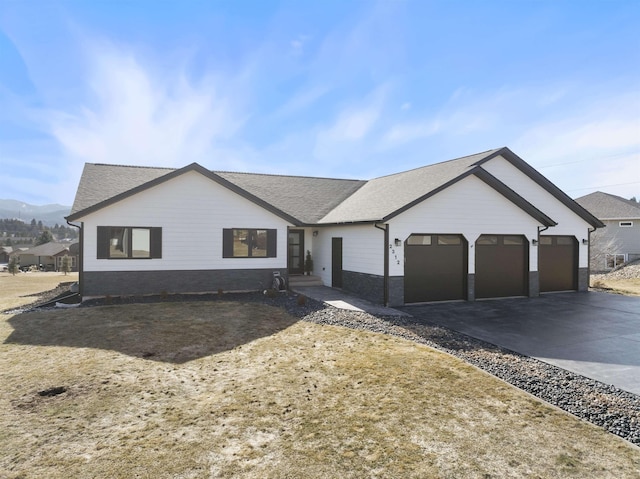 ranch-style house with concrete driveway, a shingled roof, an attached garage, and stone siding