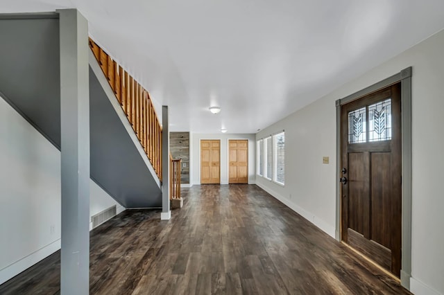 entrance foyer featuring stairs, visible vents, dark wood-style floors, and baseboards