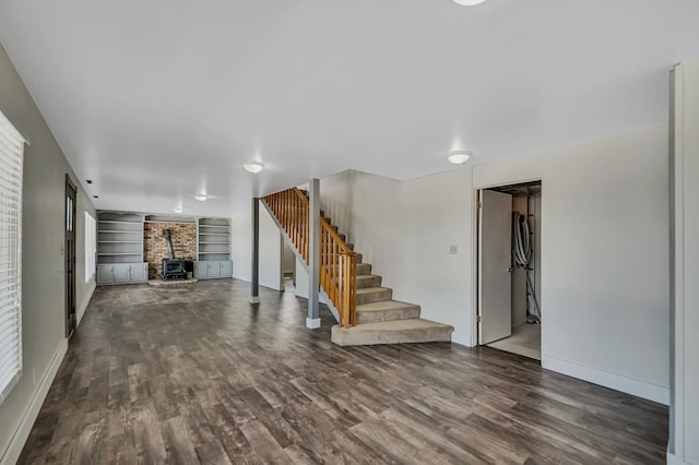 interior space featuring stairway, a wood stove, built in shelves, and wood finished floors