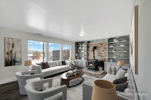 living room with dark wood-style floors, visible vents, a wood stove, and baseboards