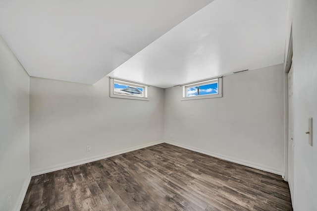 basement featuring baseboards and dark wood-style flooring