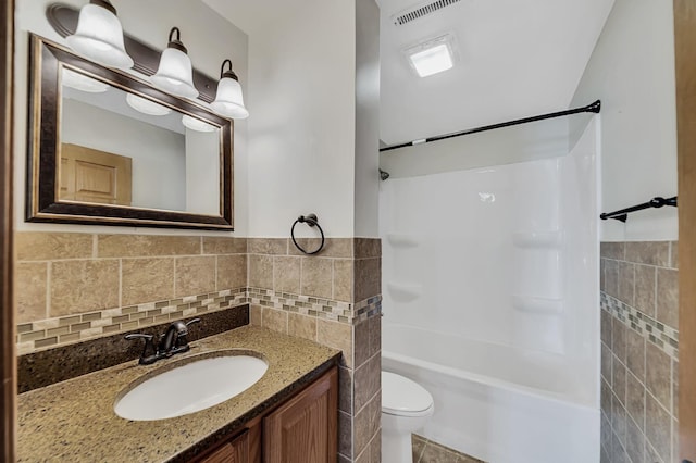 bathroom with visible vents, toilet, tile walls, washtub / shower combination, and vanity