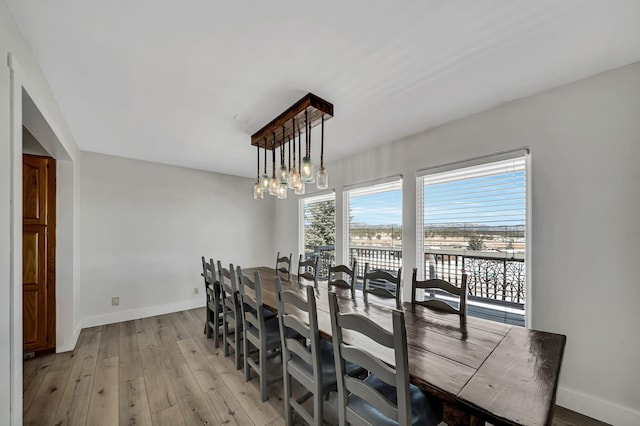 dining space featuring a chandelier, baseboards, and light wood-style flooring