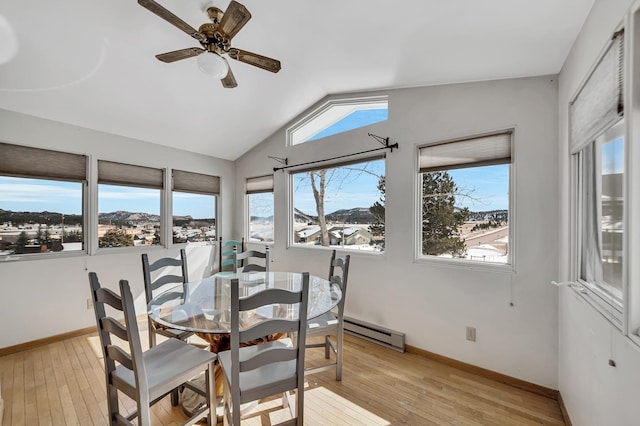 dining area featuring a baseboard heating unit, baseboards, light wood-style flooring, and vaulted ceiling