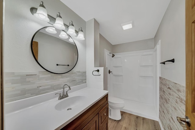 bathroom featuring vanity, wood finished floors, toilet, and a shower