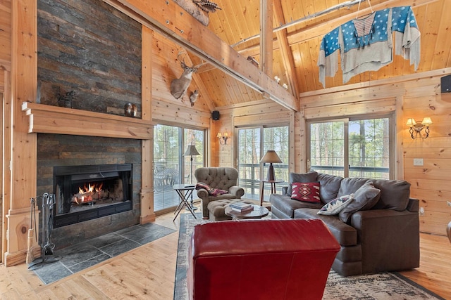 living area featuring a fireplace with flush hearth, wood walls, beam ceiling, wooden ceiling, and wood finished floors