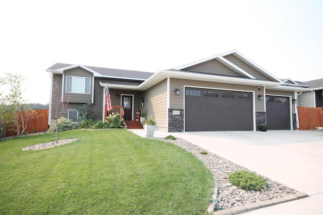 view of front of house featuring stone siding, fence, concrete driveway, a front yard, and an attached garage