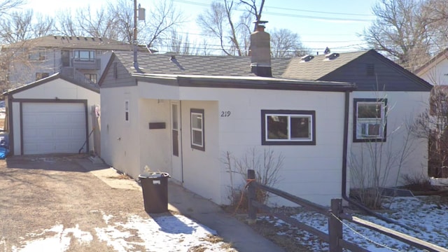 view of front of property with a chimney, a shingled roof, and an outdoor structure