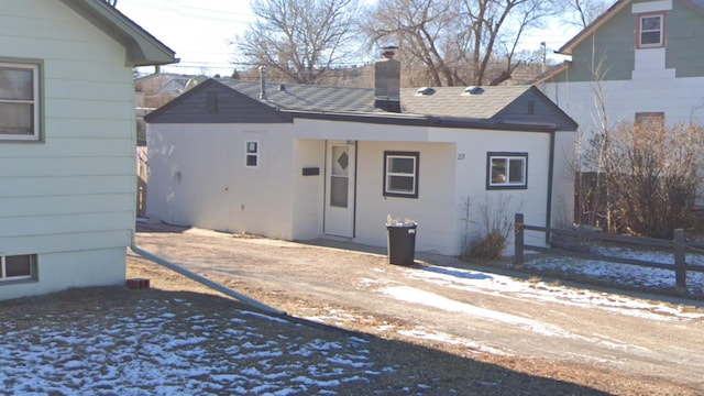 back of property featuring roof with shingles, a chimney, and fence