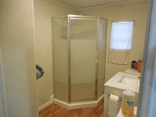 bathroom featuring a shower stall, vanity, ornamental molding, and wood finished floors