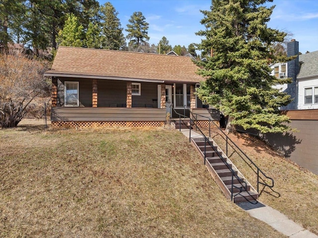 single story home featuring covered porch, a shingled roof, and a front lawn