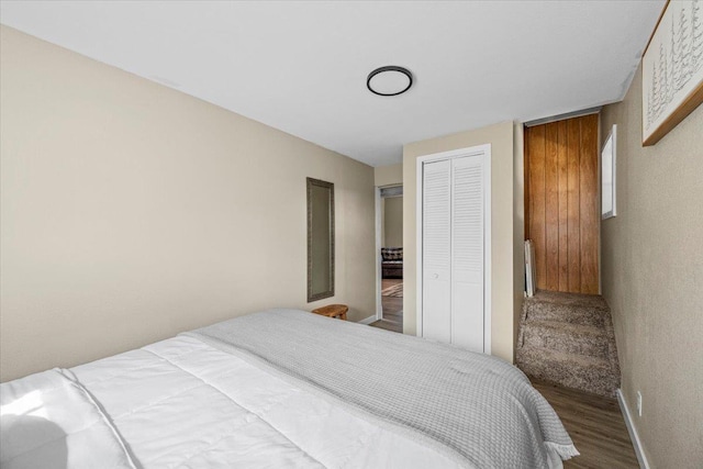 bedroom with a closet, radiator heating unit, baseboards, and wood finished floors