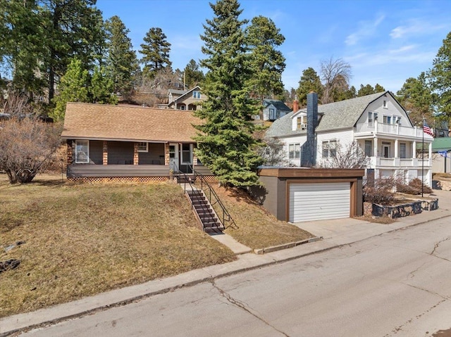 view of front of property with a gambrel roof, a front lawn, covered porch, concrete driveway, and stairs