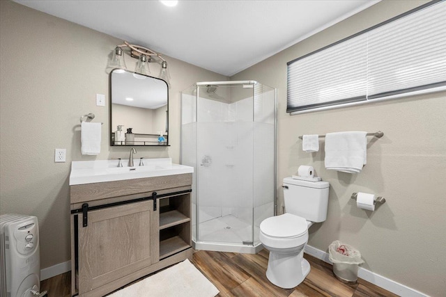 bathroom with a shower stall, baseboards, toilet, wood finished floors, and vanity