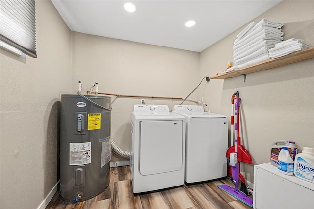 laundry area with water heater, laundry area, washing machine and dryer, and wood finished floors