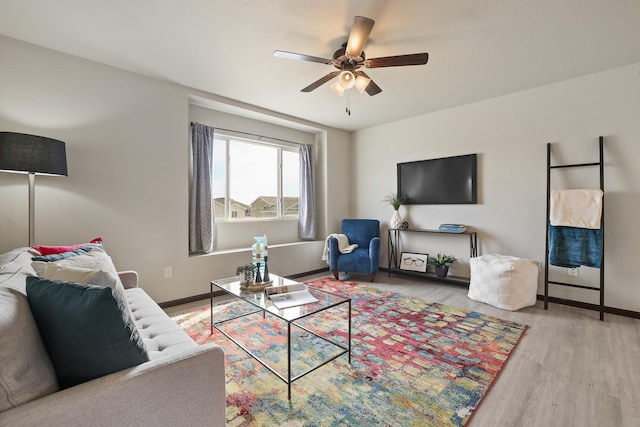 living room featuring baseboards, a ceiling fan, and wood finished floors