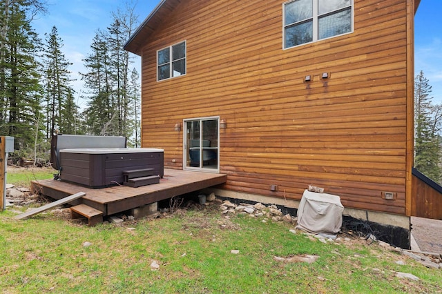 rear view of house with a wooden deck, a lawn, and a hot tub