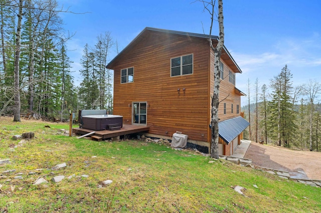 back of house with a deck, a lawn, driveway, and a hot tub