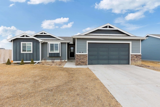 craftsman-style house featuring board and batten siding, fence, driveway, stone siding, and an attached garage