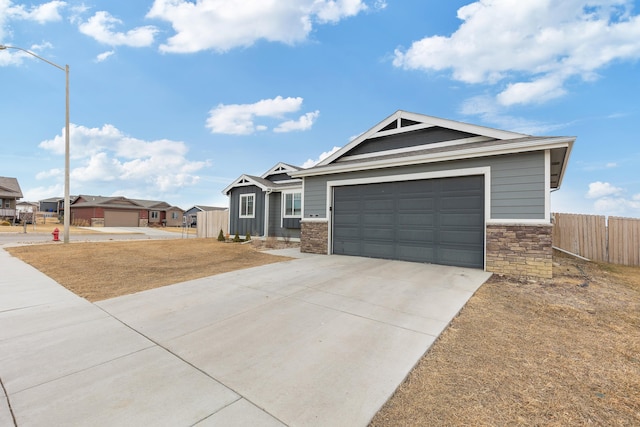 craftsman inspired home with concrete driveway, an attached garage, fence, and stone siding