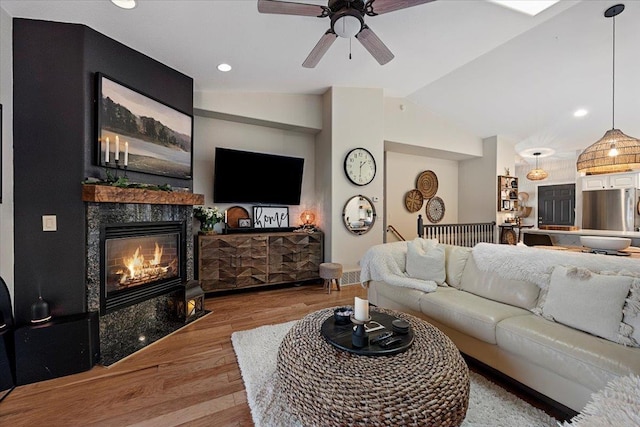 living room featuring wood finished floors, a ceiling fan, lofted ceiling, a fireplace, and recessed lighting