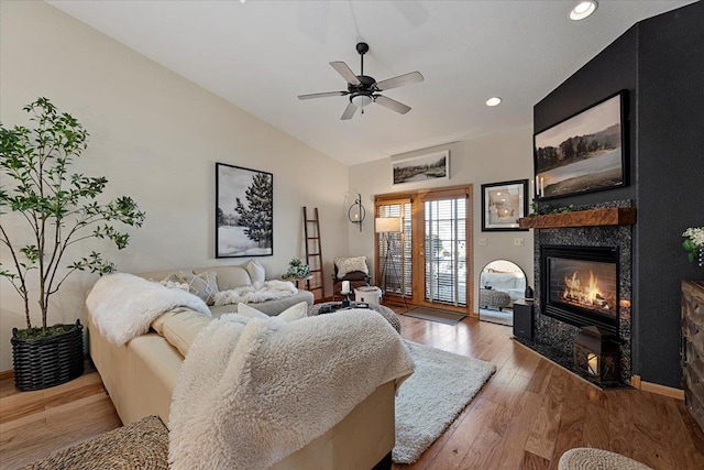 living room with a ceiling fan, hardwood / wood-style flooring, vaulted ceiling, and a tile fireplace