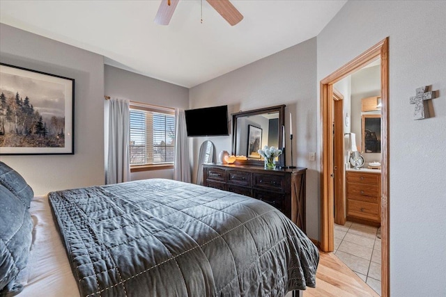 bedroom with light tile patterned floors, a ceiling fan, and connected bathroom