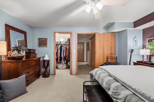 bedroom with a spacious closet, baseboards, ceiling fan, carpet, and a closet