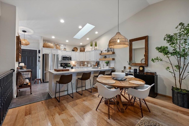 dining room with a skylight, recessed lighting, light wood finished floors, and high vaulted ceiling