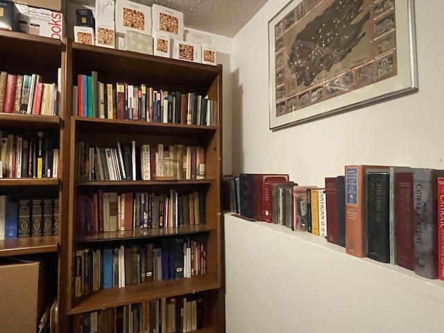 sitting room with wall of books and a textured ceiling