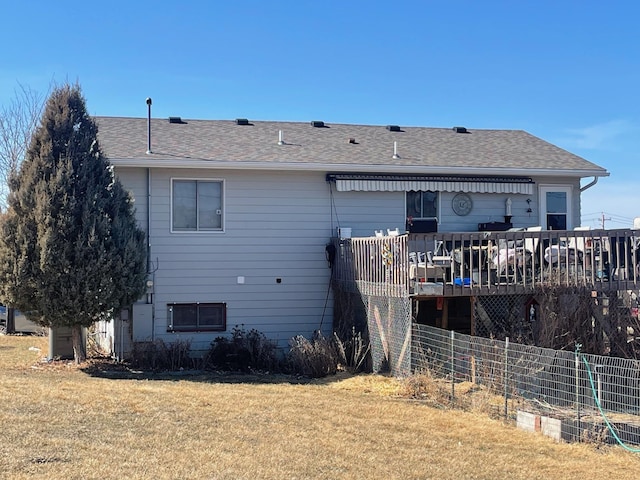 rear view of property featuring a lawn and a shingled roof