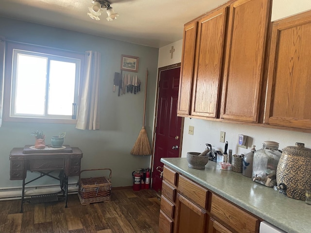 kitchen featuring a baseboard heating unit, baseboards, dark wood finished floors, white dishwasher, and brown cabinetry