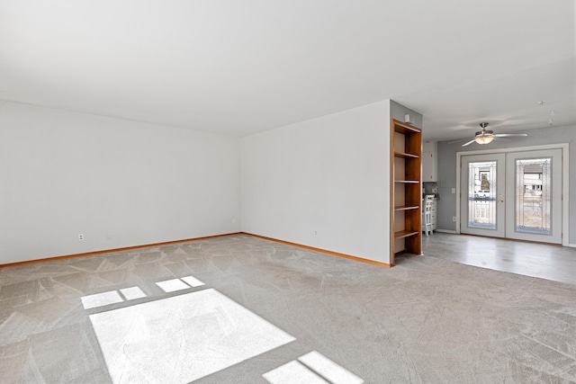 empty room with light colored carpet, baseboards, french doors, and ceiling fan