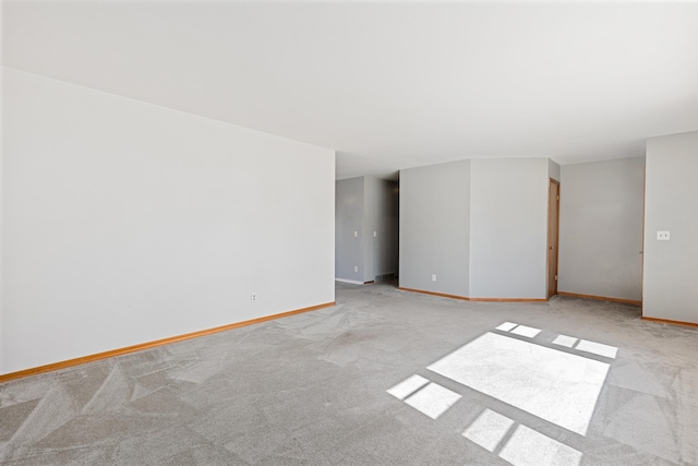 unfurnished room featuring baseboards and light carpet