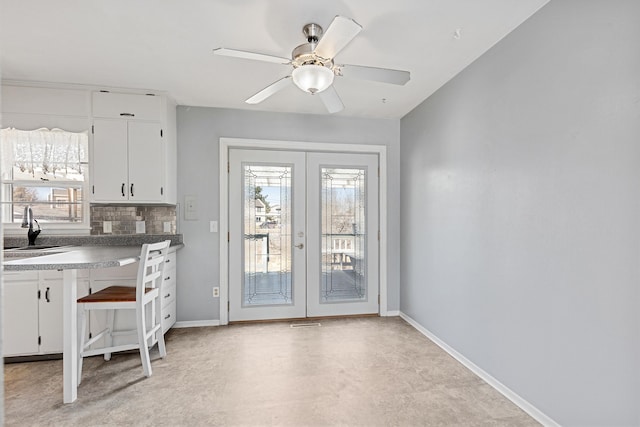 unfurnished dining area featuring ceiling fan, french doors, baseboards, and a sink