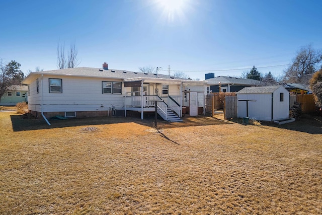 back of house featuring a storage unit, an outbuilding, a lawn, and fence