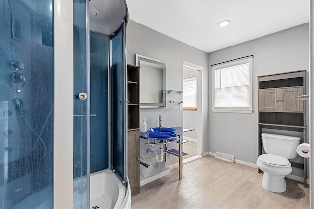 bathroom featuring a shower with door, baseboards, toilet, a bathtub, and wood finished floors