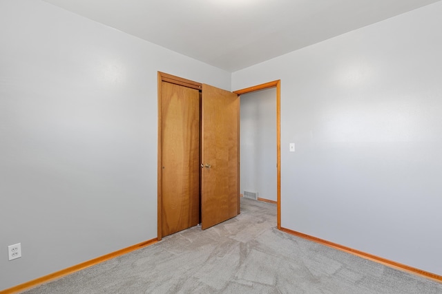 spare room with visible vents, baseboards, and light carpet