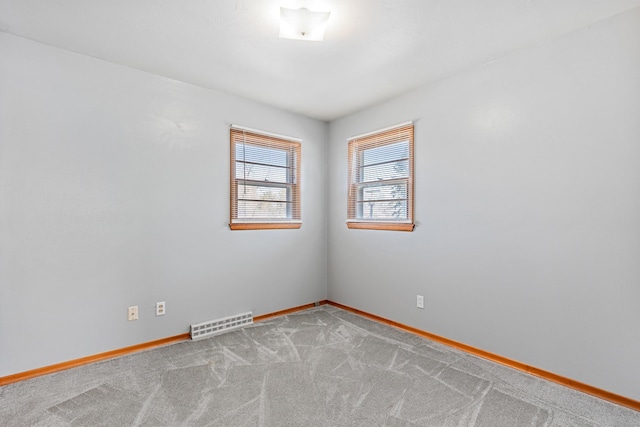 carpeted spare room with visible vents and baseboards