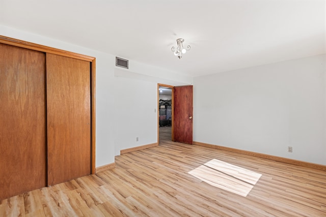 unfurnished bedroom with light wood-type flooring, visible vents, baseboards, and a closet