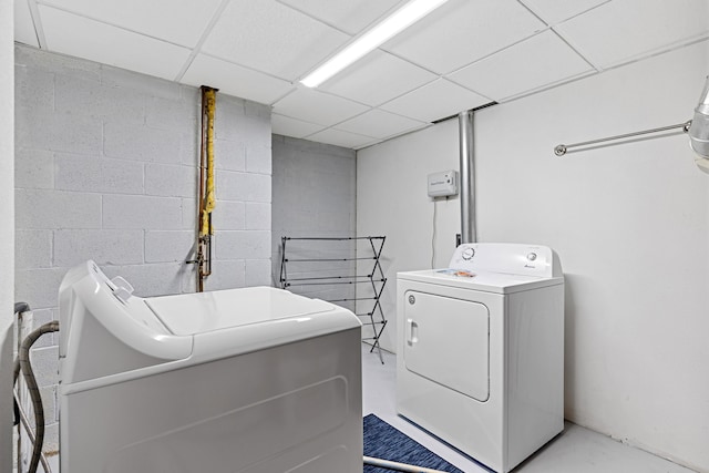 clothes washing area featuring laundry area, concrete block wall, and washer and clothes dryer