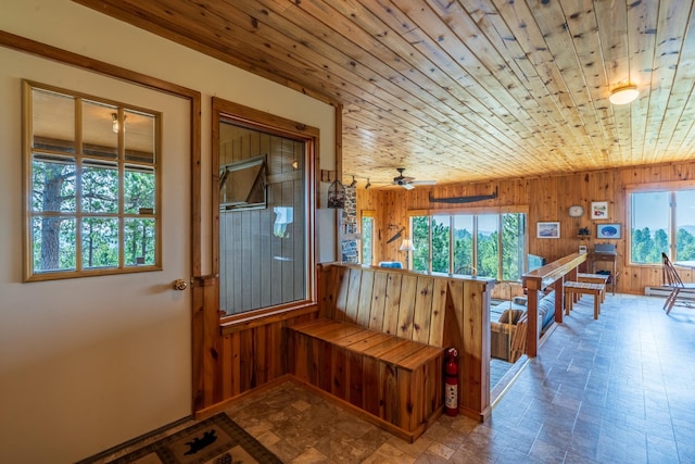 interior space featuring stone finish flooring, baseboards, wooden walls, and wood ceiling