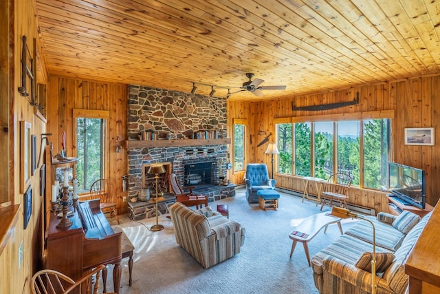 carpeted living area with a stone fireplace, a healthy amount of sunlight, wooden ceiling, and wood walls