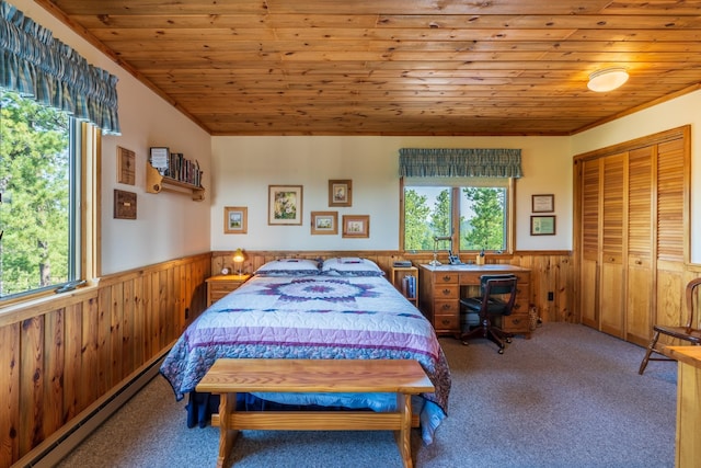 carpeted bedroom with a wainscoted wall, baseboard heating, wooden ceiling, and wooden walls