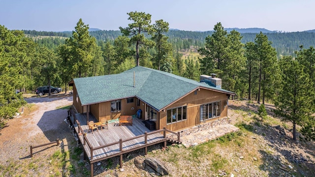 back of house with a deck, a view of trees, and dirt driveway