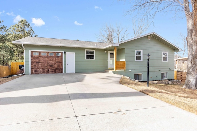 ranch-style house with concrete driveway, fence, a garage, and roof with shingles